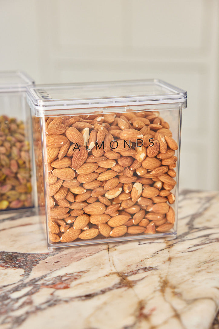 Clear container filled with almonds on a marble surface