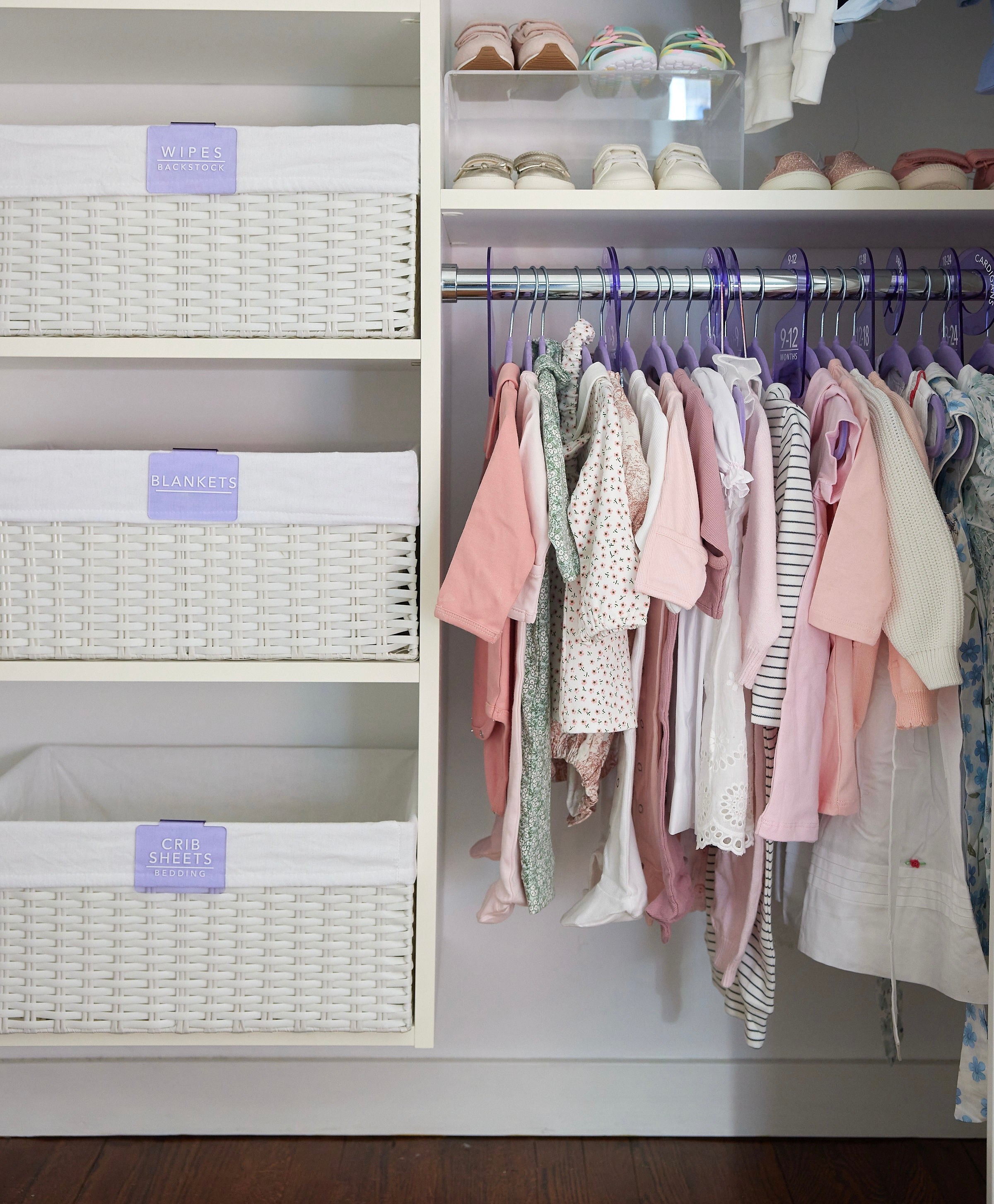Closet with baby clothes on hangers and storage baskets.