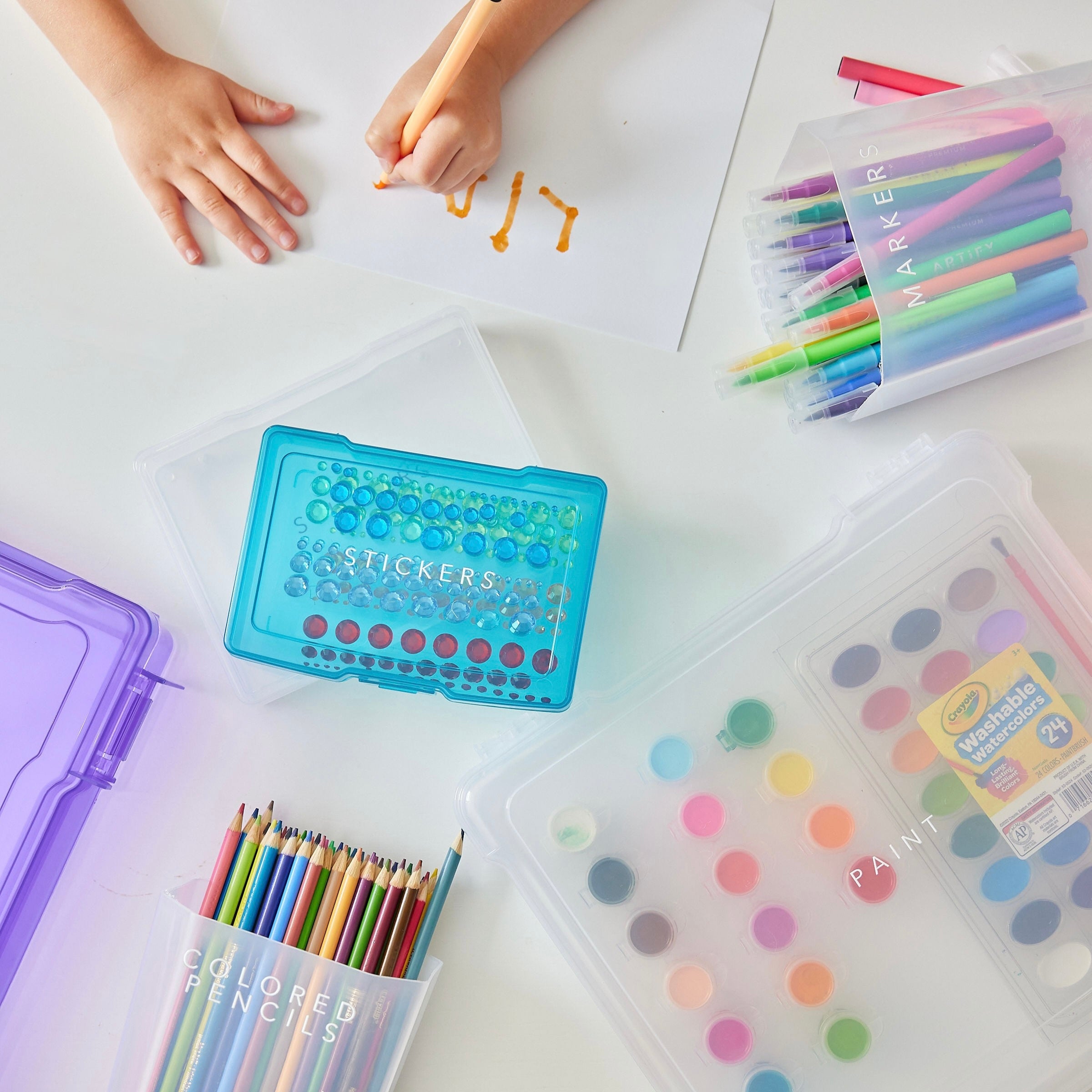 Colorful stationery items including crayons and markers on a white surface.