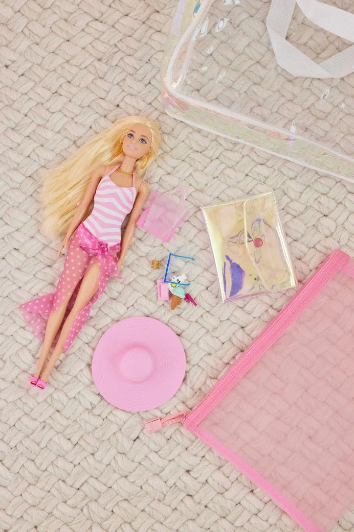 Barbie doll with pink swimsuit and accessories on a textured surface
